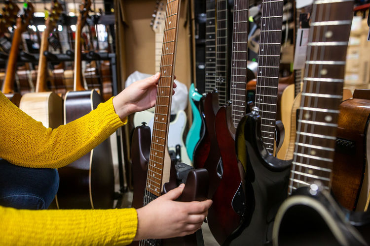 Midsection of woman playing guitar at store