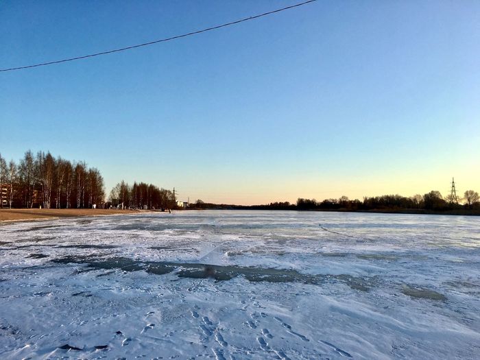 Scenic view of frozen field against clear blue sky