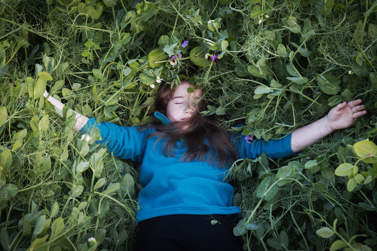 MIDSECTION OF WOMAN WITH PLANTS IN FIELD