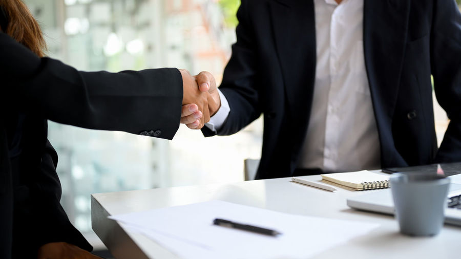 Midsection of business colleagues shaking hands in office