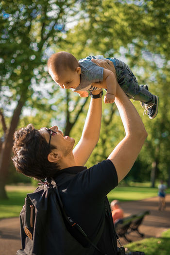 Side view of father holding aloft son at hyde park