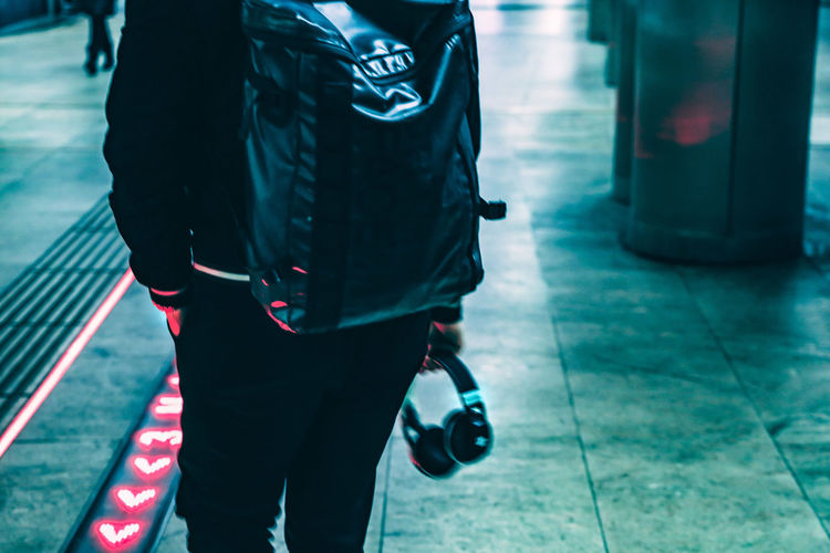 Low section of man with umbrella walking on tiled floor