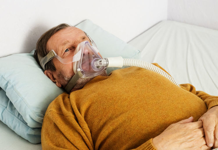 Senior man wearing oxygen mask lying on hospital bed