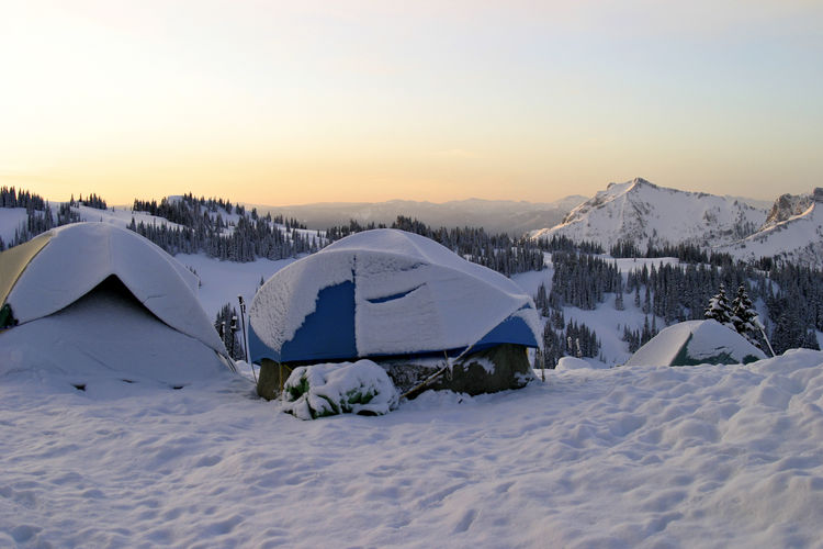 A small group of tents located together on mount rainier after a snowstorm.