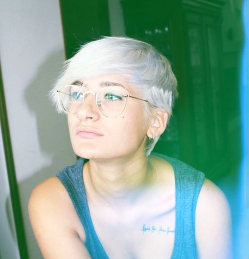 Young woman with short dyed hair wearing eyeglasses at home