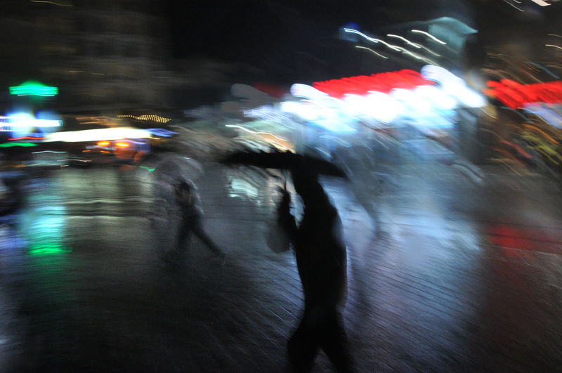 Blurred motion of people walking on wet road in rainy season