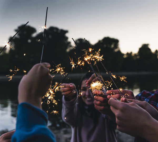 Group of friends at the riverside holding sparklers in the evening