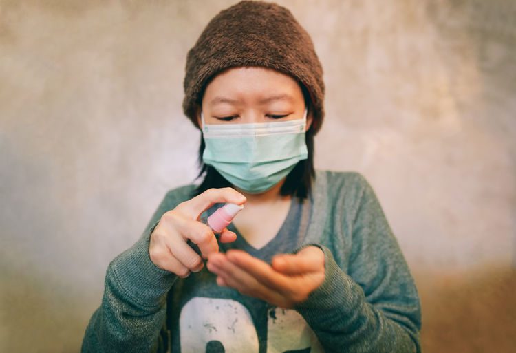 Girl with mask applying sanitizer