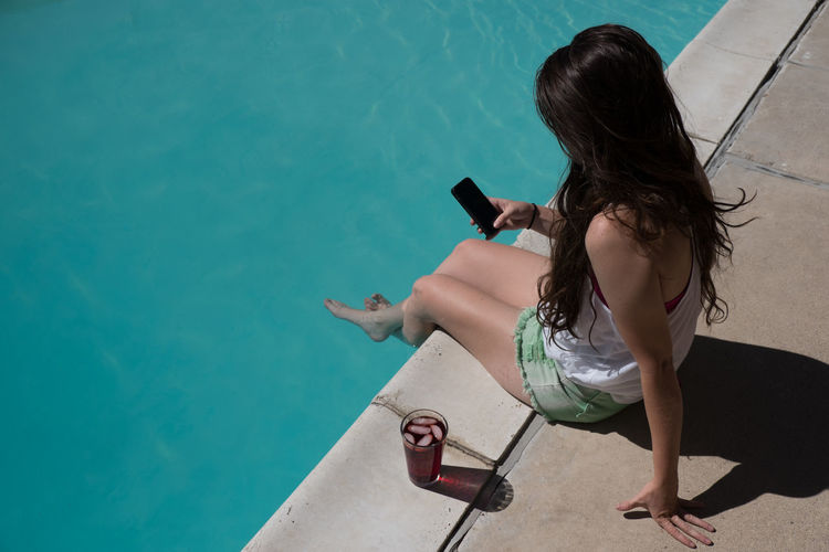 High angle view of woman using phone at poolside