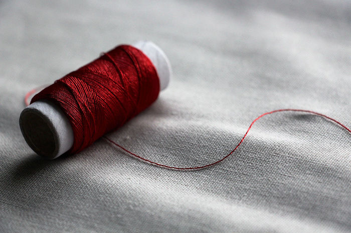 Close-up of red thread spool on fabric