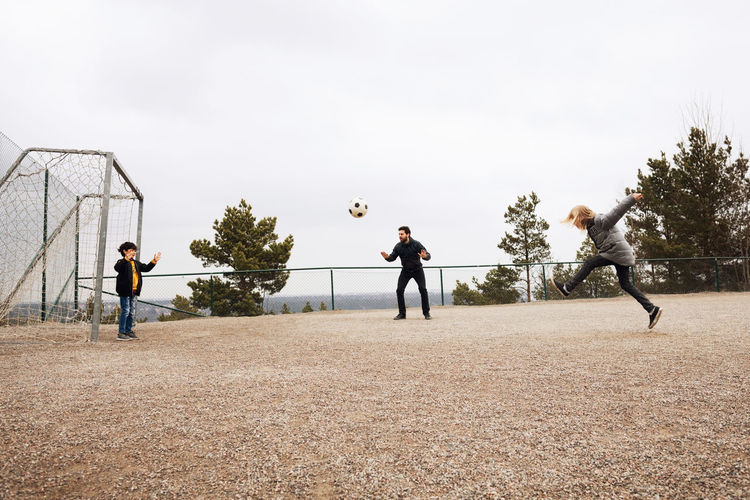 People playing soccer against sky