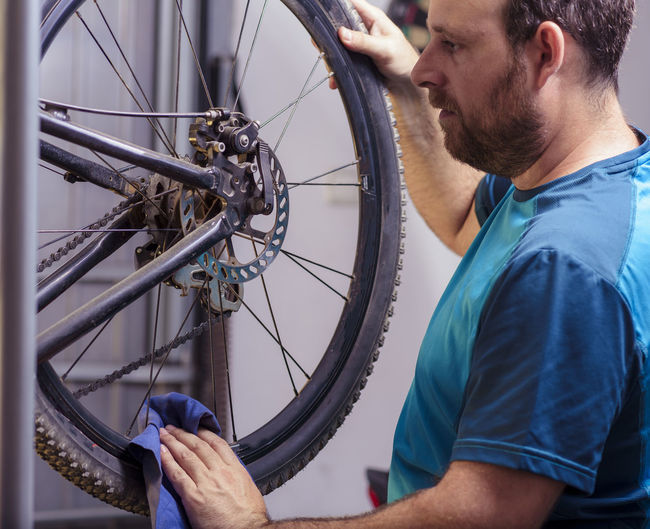 Midsection of man repairing bicycle at garage