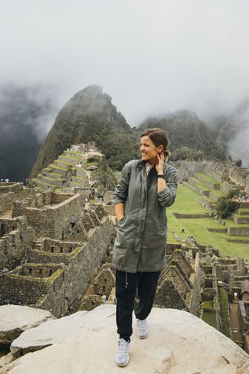 A young woman is standing near ruins of machu picchu, peru
