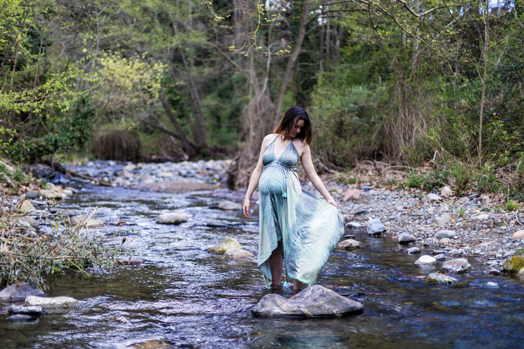 Woman standing by stream in forest