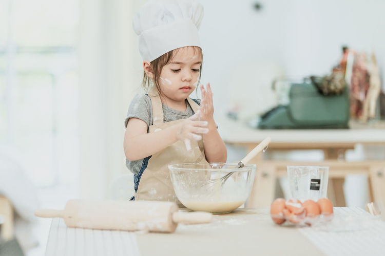 Midsection of baby girl in bowl on table at home