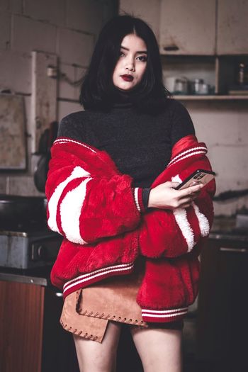 Portrait of beautiful young woman standing against red wall