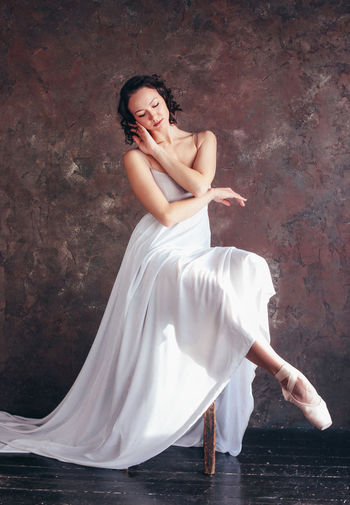 Full length of young woman dancing against wall in dance studio