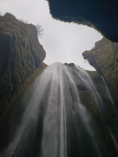 Upward view of waterfall and rocky landscape