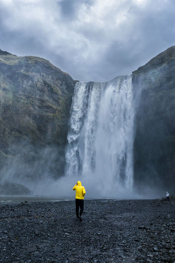 Rear view of man standing against waterfall