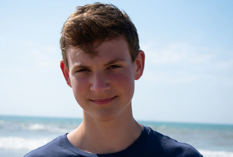 Portrait of smiling young man standing against sea