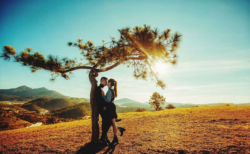 People standing by tree on field against sky