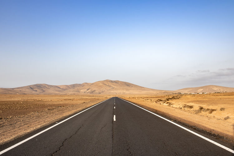 Deserted road with mountains in the background in arid landscape on fuerteventura canary islands