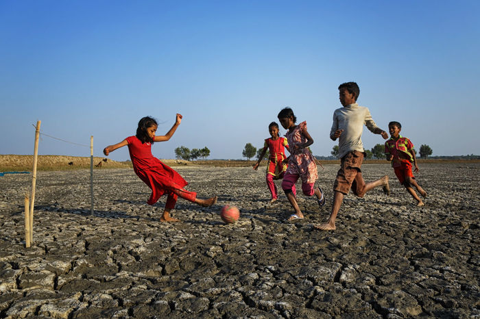CHILDREN PLAYING ON FIELD AGAINST SKY