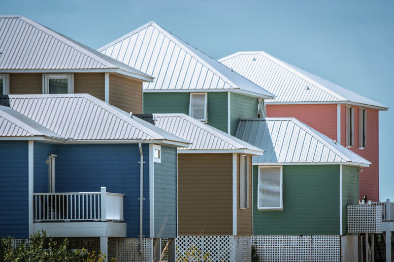 Houses in sea against buildings against clear blue sky