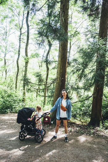 Woman standing in forest with daughter and baby stroller