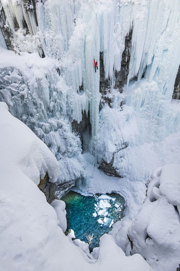 High angle view of woman climbing on snowcapped mountain during winter