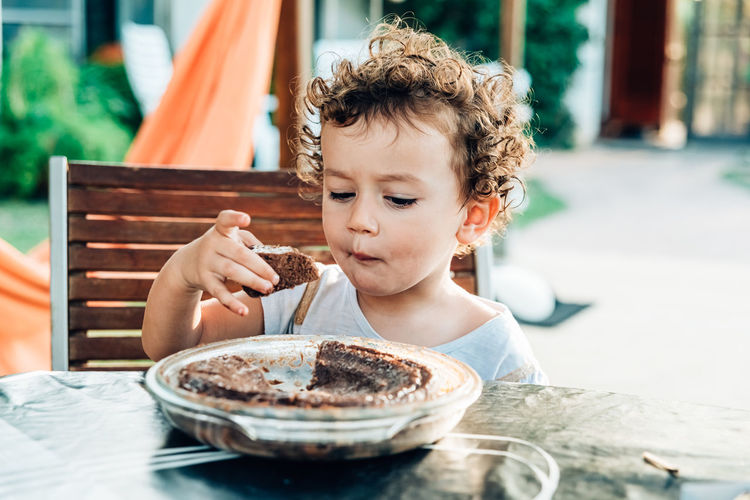 Happy boy with ice cream in bowl on table
