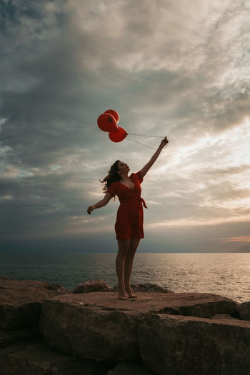 Full length of man standing on rock at beach against sky