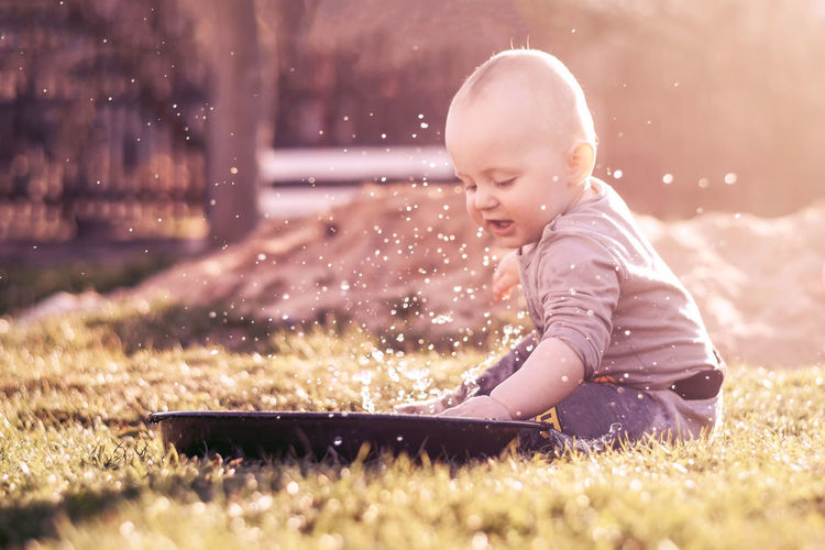 Cute boy playing with water on field