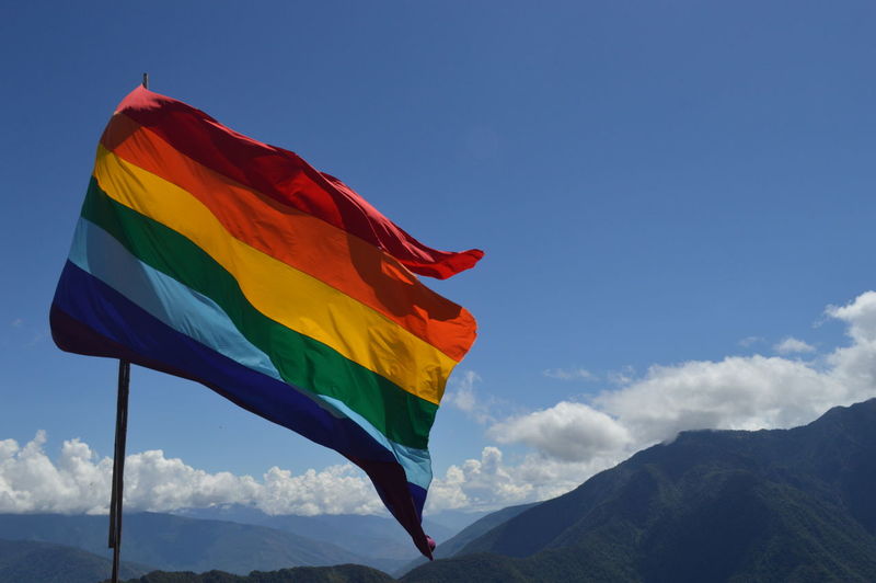 Low angle view of rainbow flag against blue sky