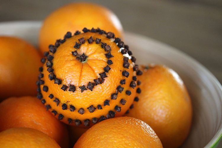 Close-up of oranges with cloves in bowl on table
