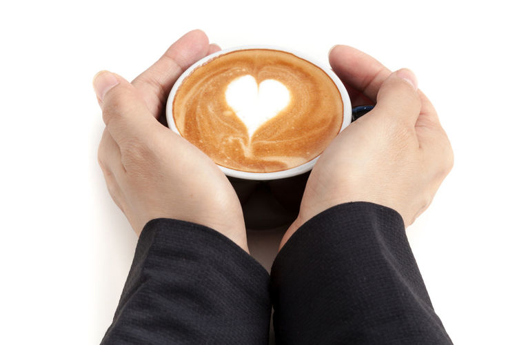 Close-up of hand holding coffee cup over white background