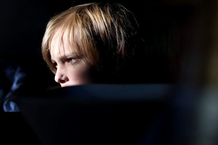 Close-up of thoughtful boy looking away in darkroom