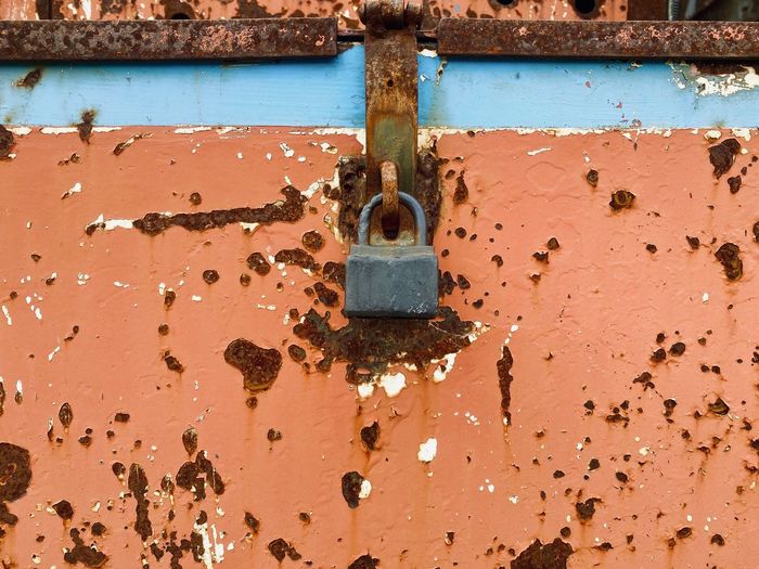 Close-up of rusty padlock on metal door