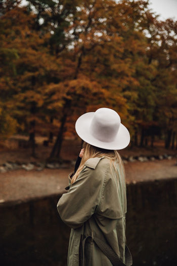 Rear view of woman wearing hat standing against trees