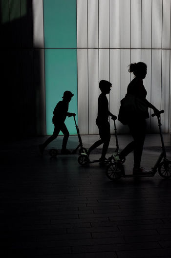 Silhouette of three people on scooters