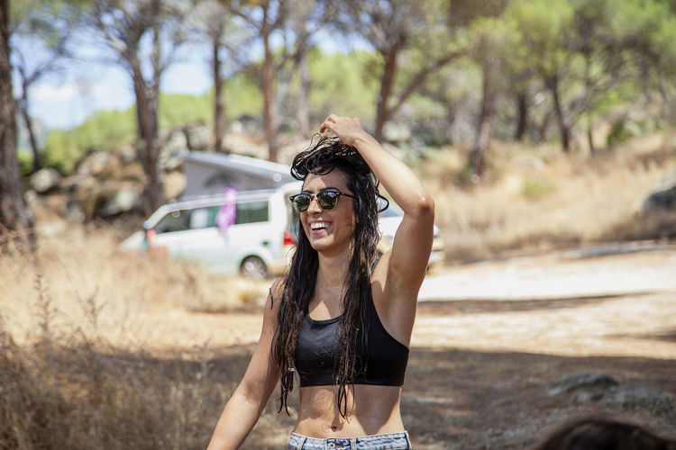 Portrait of young woman wearing sunglasses standing against car