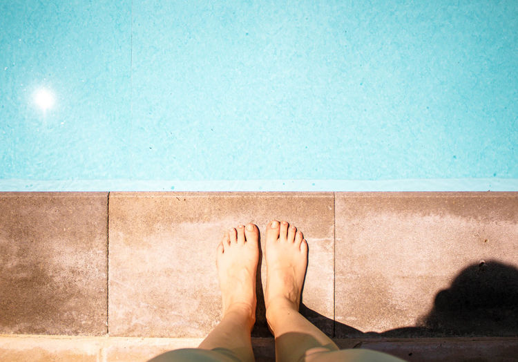 Female legs and feet in blue swimming pool