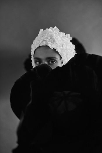 Portrait of a woman face covered with fabric against wall