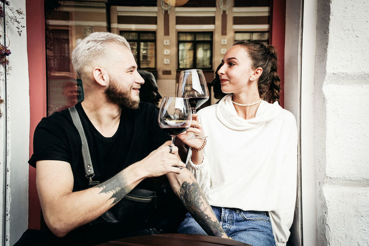 Young couple holding wineglass while sitting at cafe