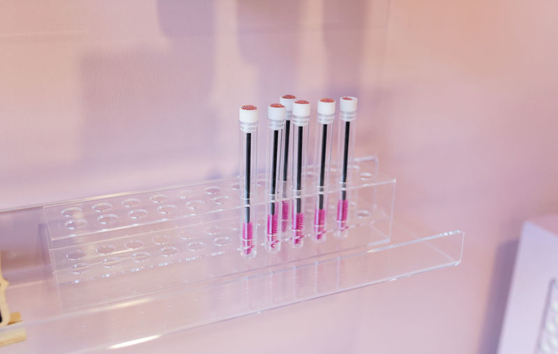 Collection of small eyelash brushes in individual case placed on vanity table in modern light beauty salon