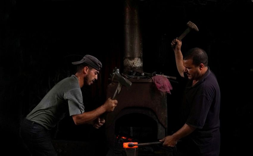 Two blacksmiths striking an iron while it's hot.