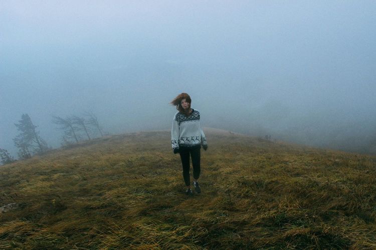 Full length of woman walking on field during foggy weather