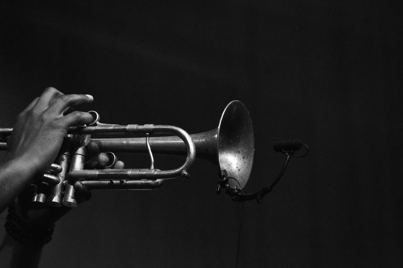 Cropped hand playing trumpet against black background