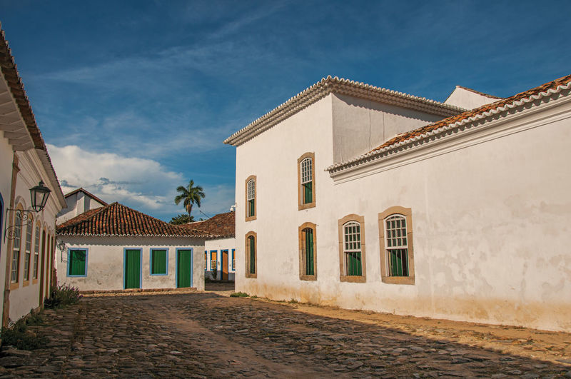 Overview of cobblestone street with old houses under blue sunny sky in paraty, brazil