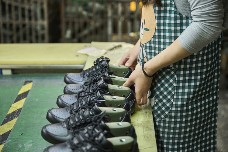 Detail of woman's hands while checking the shoes in quality control production line in chinese shoes factory
